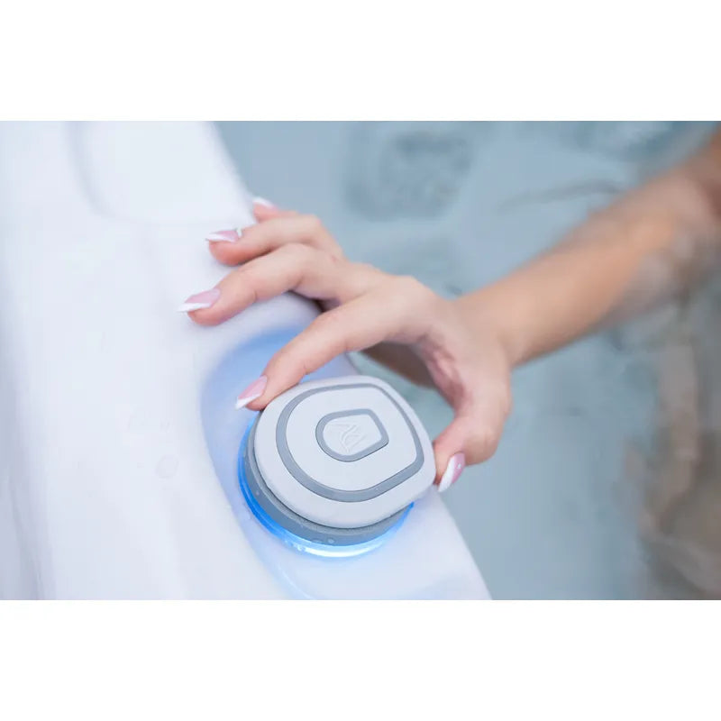 Hand operating the control panel of the Wellis Teide Life Hot Tub with illuminated control button