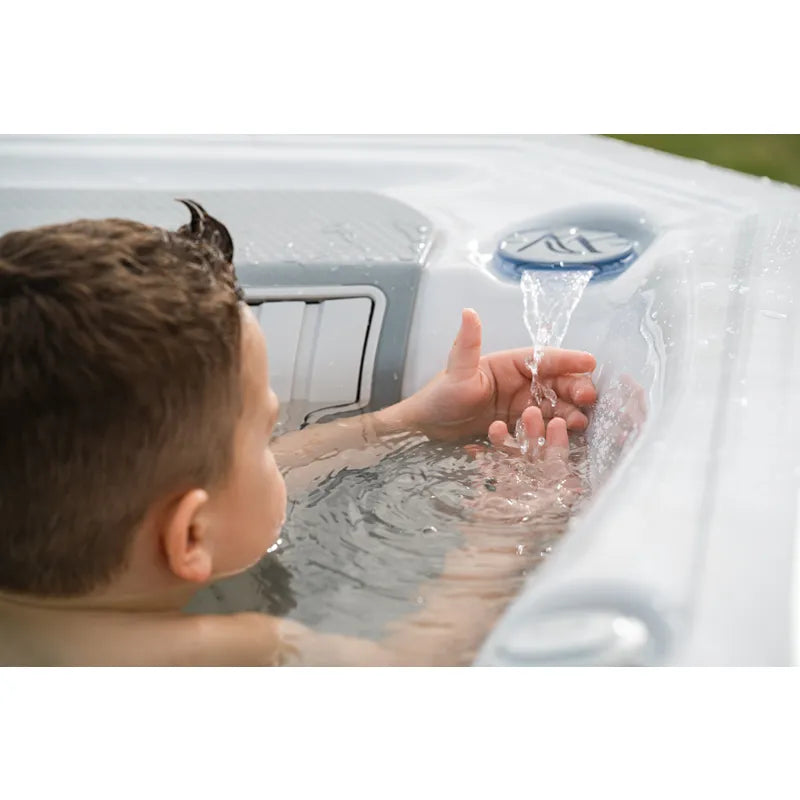Wellis Teide Life Whirlpool mit Kind, das Wasser-Jet genießt, weiße Wannen-Details und blaue Steuerung sichtbar