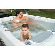 Wellis Teide Life Whirlpool mit Familie im Garten, Eltern und Kind genießen das warme Wasser mit Jets