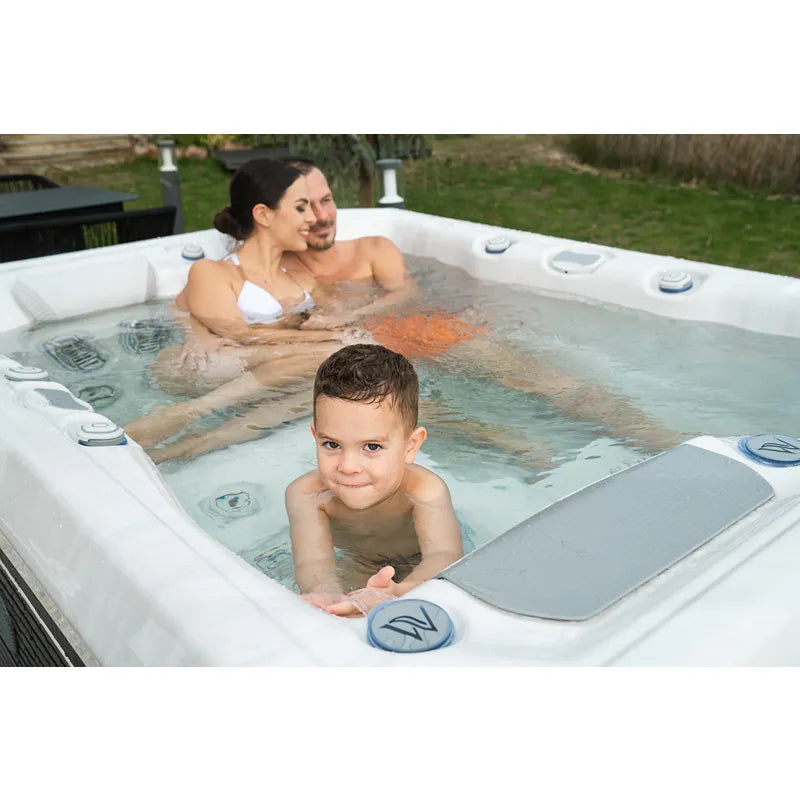 Wellis Teide Life Whirlpool mit Familie im Garten, Eltern und Kind genießen das warme Wasser mit Jets