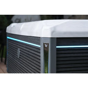 Wellis Teide Life Premium Whirlpool mit weißem Rand, schwarzem Holzdekor und blauer LED-Beleuchtung im Garten