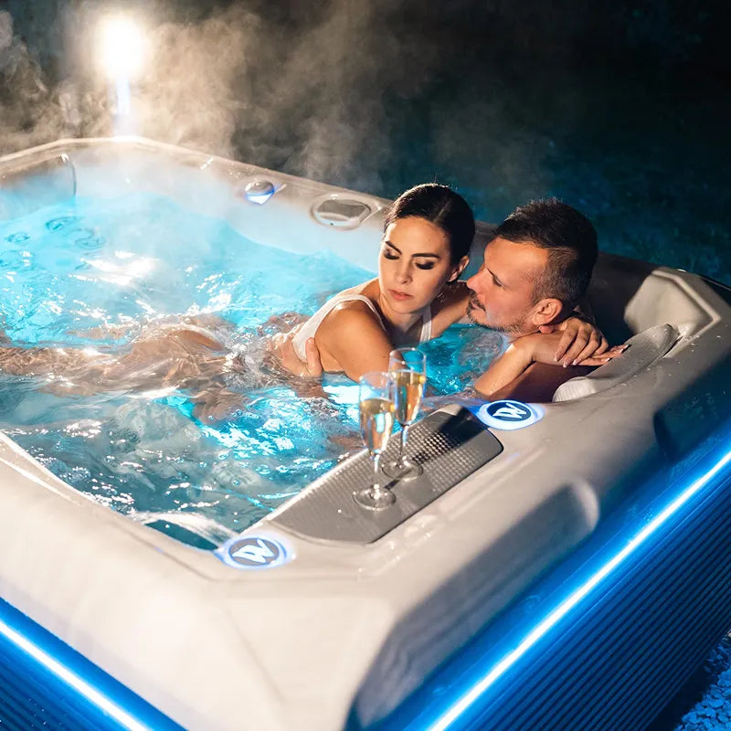 Wellis Teide Life Premium Whirlpool mit Paar beim Entspannen, dampfend, blaues Wasser, 3 Sitze mit Jets