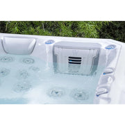 Wellis Teide Life Premium Whirlpool mit 32 Jets und aktiven Wasserfontänen im Garten, umgeben von grünen Hecken