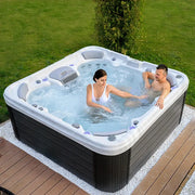 Wellis Vienna Life Premium-Whirlpool mit zwei Personen in blauem Wasser auf Terrasse mit Garten