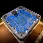 Wellis Vienna Life Premium-Whirlpool mit blauem Wasser, LED-Beleuchtung und Massagedüsen auf Holzterrasse bei Nacht