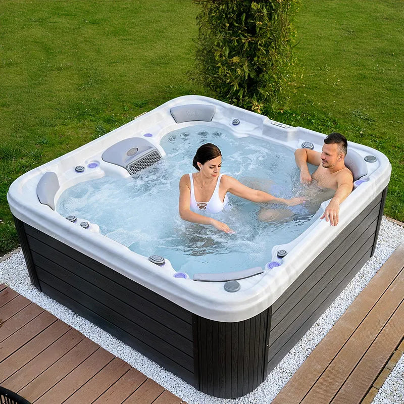 Wellis Vienna Life Premium-Whirlpool mit zwei Personen in sprudelndem Wasser, weiße Wanne mit schwarzem Sockel auf Terrasse