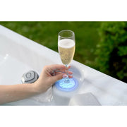Wellis Vienna Life Whirlpool mit LED-Beleuchtung, Champagnerglas in Hand über weißem Beckenrand