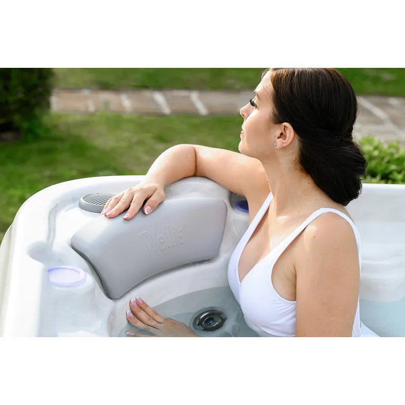 Frau entspannt sich im Wellis Vienna Life Premium-Whirlpool mit grauem Kopfkissen im Garten