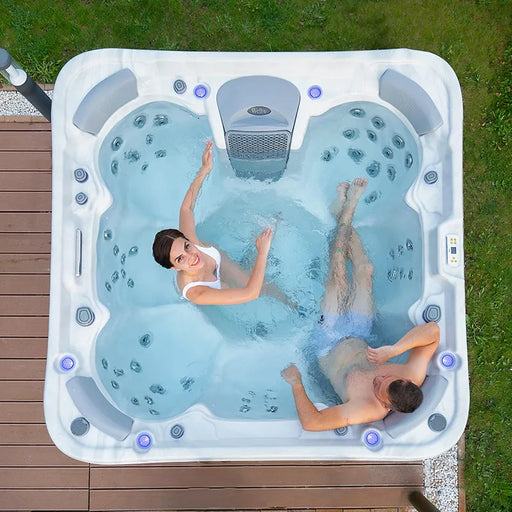 Wellis Vienna Life Premium-Whirlpool mit zwei Personen in türkisblauem Wasser, weiße Schale, Massagedüsen und Kontrollpanel in Gartensetting