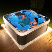Wellis Vienna Life Premium-Whirlpool mit zwei Personen in blauem Wasser auf beleuchteter Terrasse