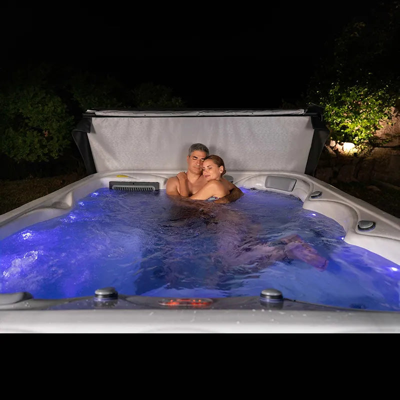 Wellis Venus – Classic Line Whirlpool 6 Personen mit zwei Personen im beleuchteten Wasser bei Nacht im Garten