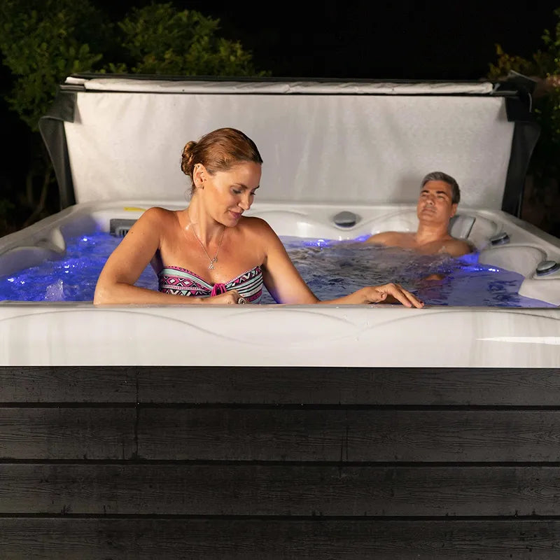 Wellis Venus – Classic Line Whirlpool 6 Personen mit zwei Personen im beleuchteten Wasser im Garten bei Nacht