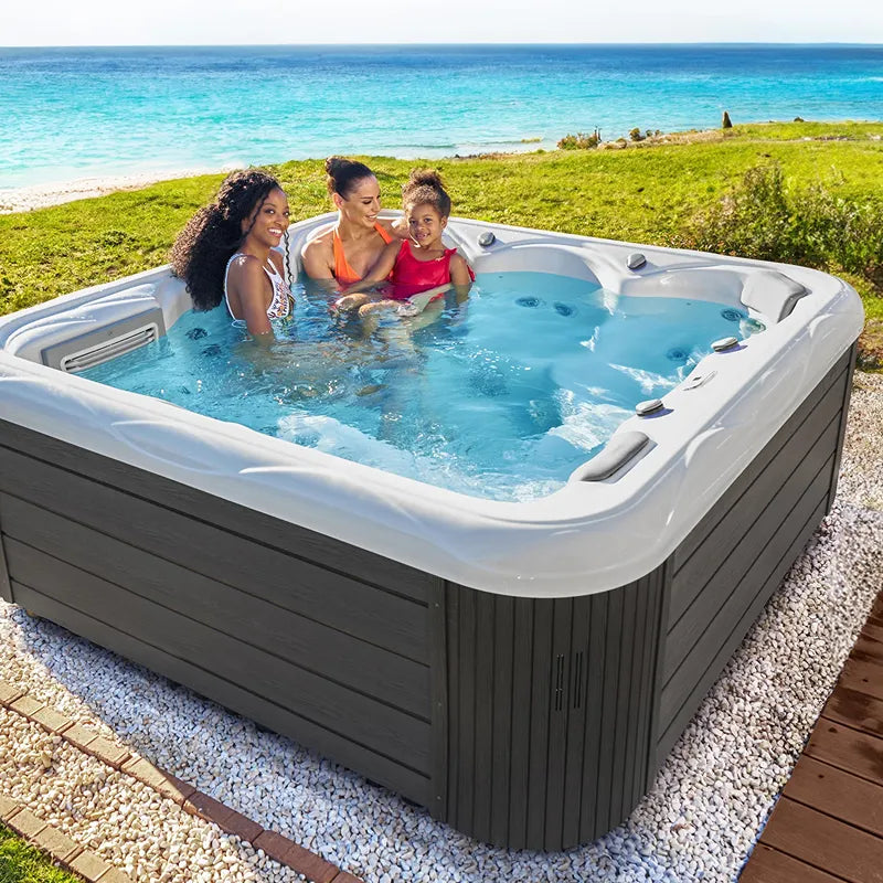Wellis Venus – Classic Line Whirlpool 6 Personen mit drei Personen im warmen Wasser, Strandkulisse im Hintergrund