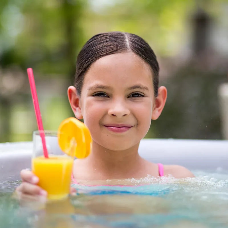 Kind in Wellis Venus – Classic Line Whirlpool 6 Personen mit Orangensaft entspannend im Wasser