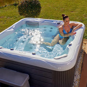 Wellis Venus – Classic Line Whirlpool 6 Personen mit Frau im Garten, Wasserstrahlen und Blasensystem sichtbar