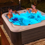 Wellis Venus – Classic Line Whirlpool 6 Personen mit LED-Beleuchtung, zwei Personen entspannen im beleuchteten Gartenbecken bei Nacht