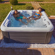 Wellis Venus – Classic Line Whirlpool 6 Personen mit zwei Personen im sprudelnden Wasser, Gartensetting