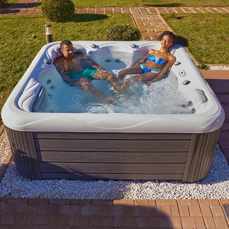 Wellis Venus – Classic Line Whirlpool 6 Personen mit zwei Personen im sprudelnden Wasser, Gartensetting