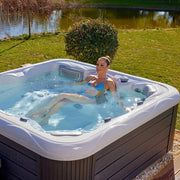 Wellis Venus – Classic Line Whirlpool 6 Personen mit Person im warmen Wasser, Gartensetting mit Teich