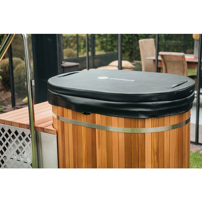 Winthera Arctic Barrel Eisbad aus Holz mit schwarzer Abdeckung auf einer Holzterrasse, Metallringe, Gartensicht